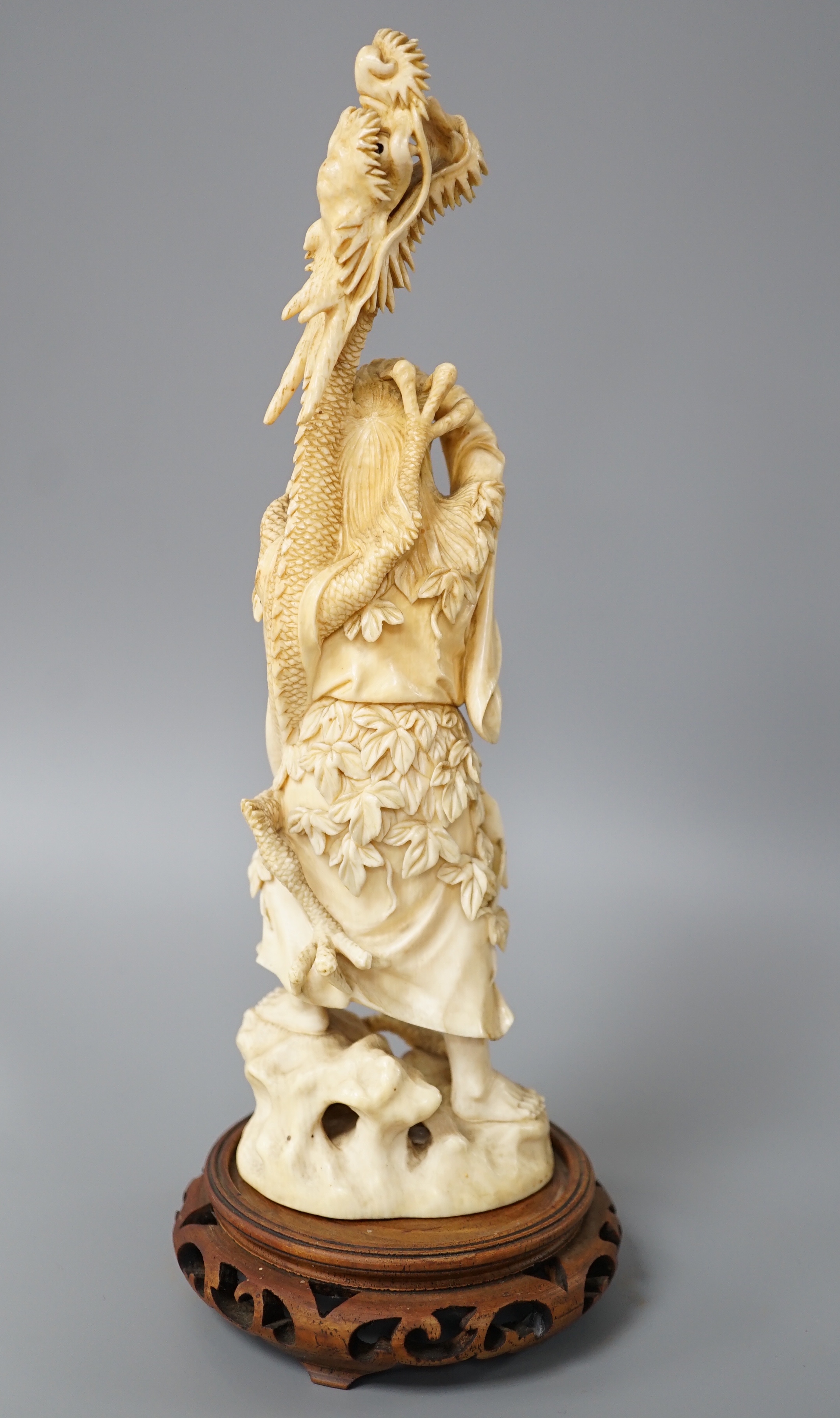 A Japanese ivory okimono of Shoshi Sennin and a dragon, early 20th century, signed, associated wood stand, 24cm excl stand